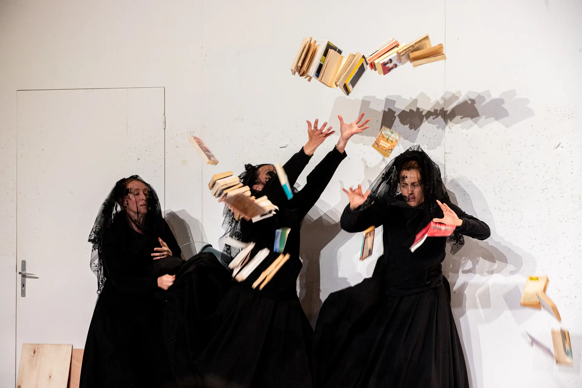 Festival di Spoleto performance: Three black-clad figures throwing books dramatically