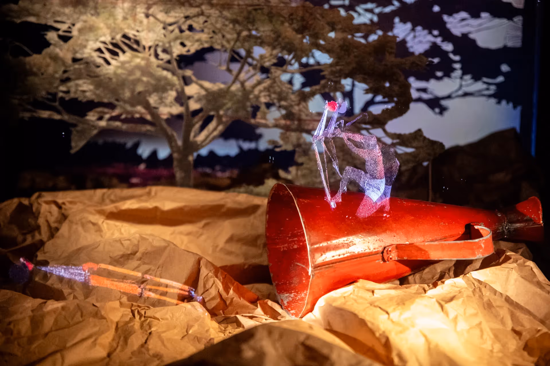 Artistic installation at Festival di Spoleto featuring illuminated figure near red megaphone