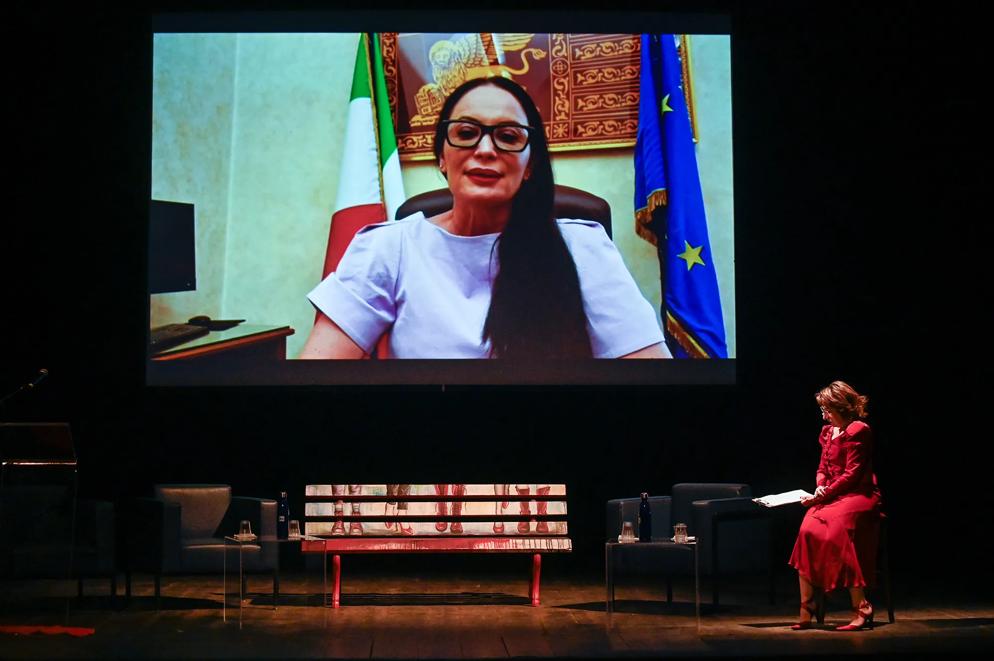 Proiezione video al Festival di Spoleto con donna in schermo e ospite sul palco