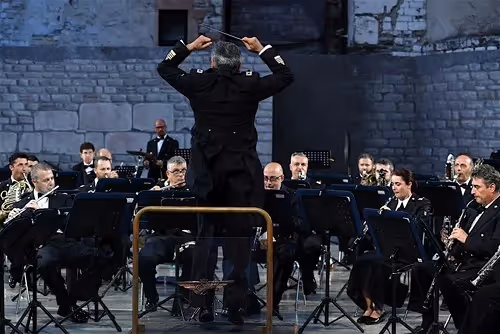 Conductor leads orchestra performance at Festival di Spoleto in stone venue
