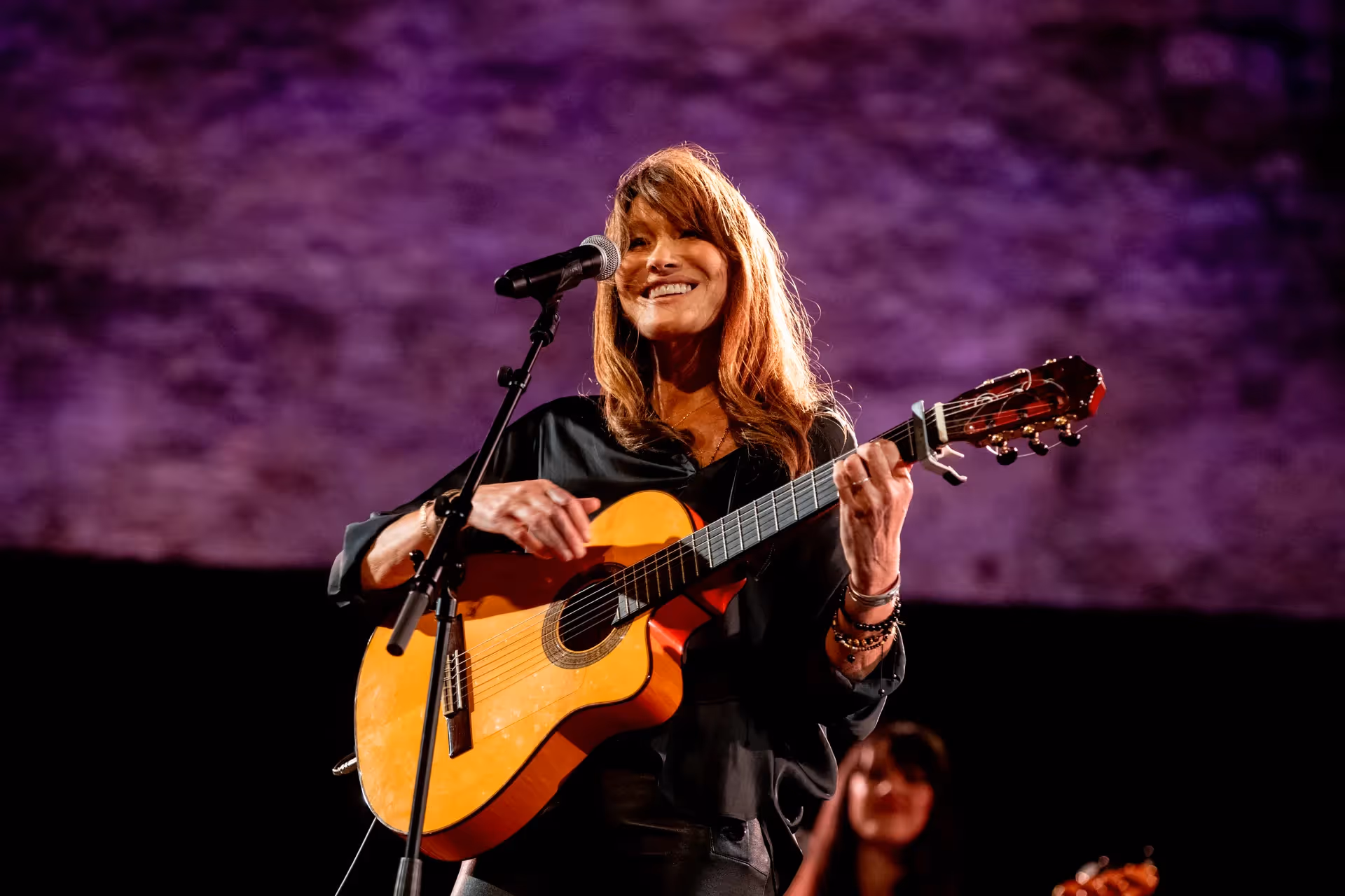 Musician performing at Festival di Spoleto with acoustic guitar and purple backdrop