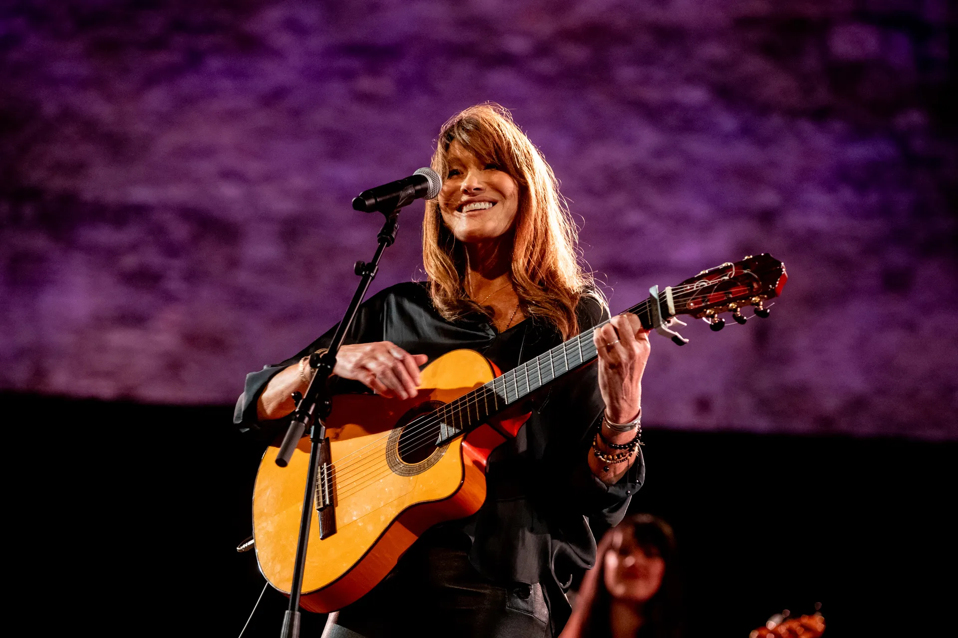 Musician performing at Festival di Spoleto with acoustic guitar and purple backdrop