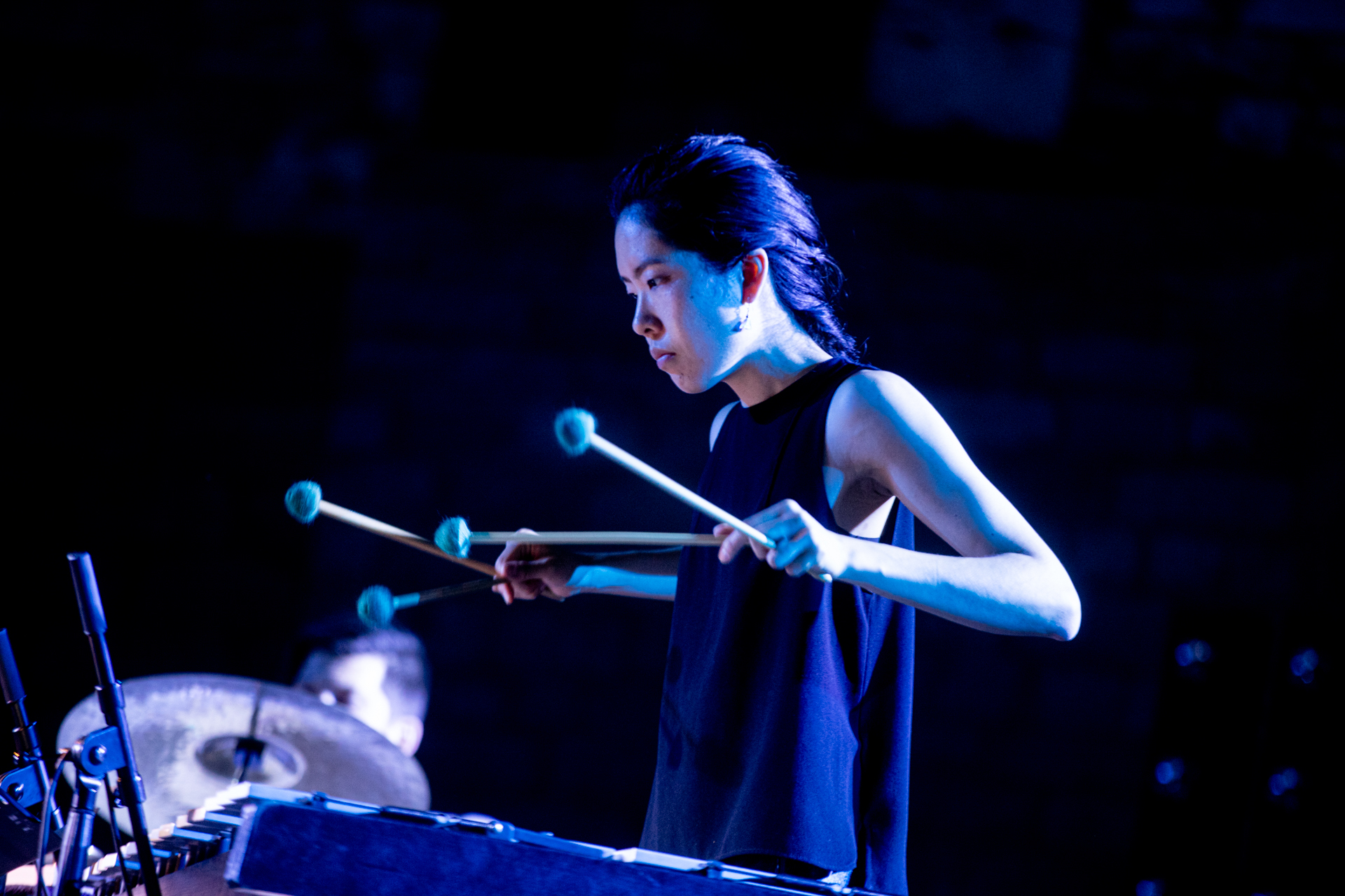 Percussionista al Festival di Spoleto, illuminata da luce blu intensa