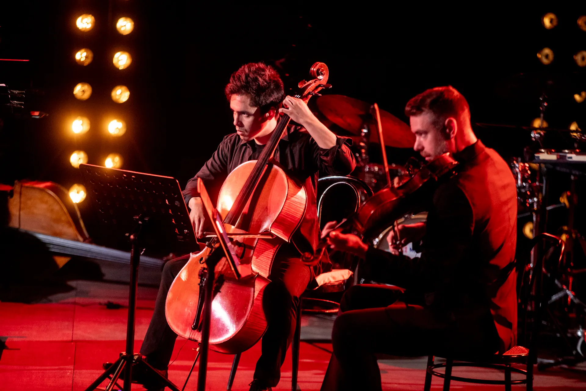 Cellist and violinist performing at Festival di Spoleto, dramatic red-lit stage