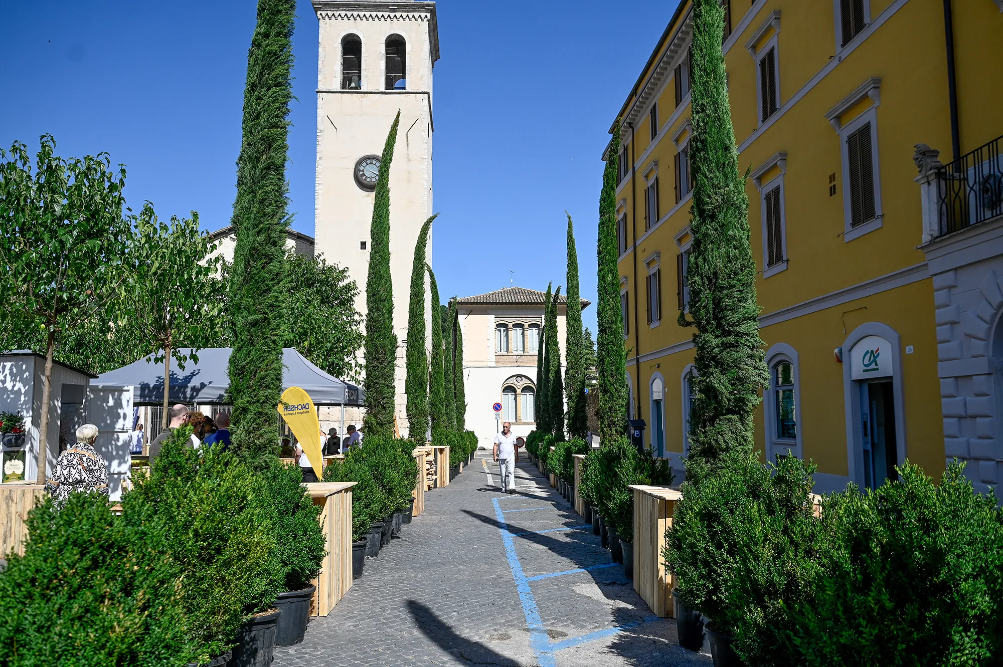 Festival di Spoleto street scene with historic tower, cypress trees, and yellow buildings