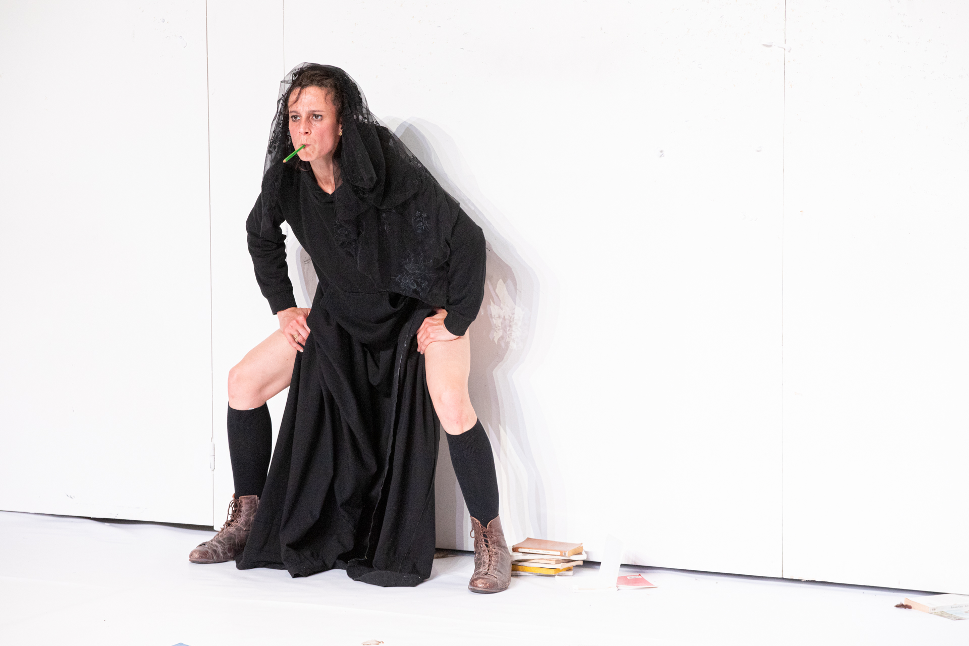 Dramatic performer at Festival di Spoleto in black attire with books nearby