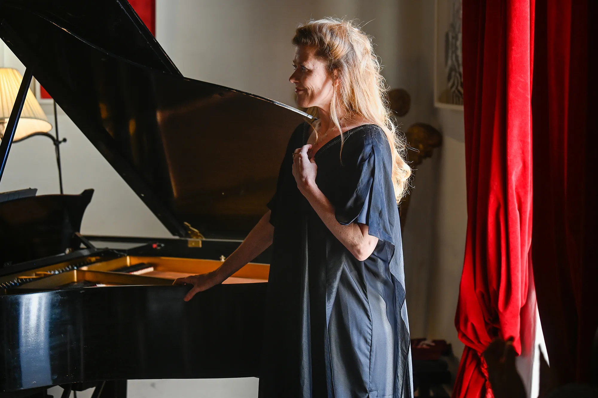 Pianist performs at Festival di Spoleto, standing near grand piano with red curtain