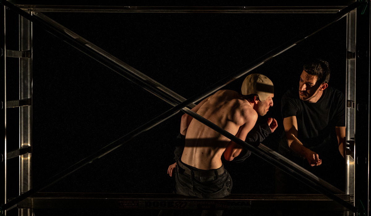 Performance drammatica al Festival di Spoleto: corpi intrappolati in una struttura metallica