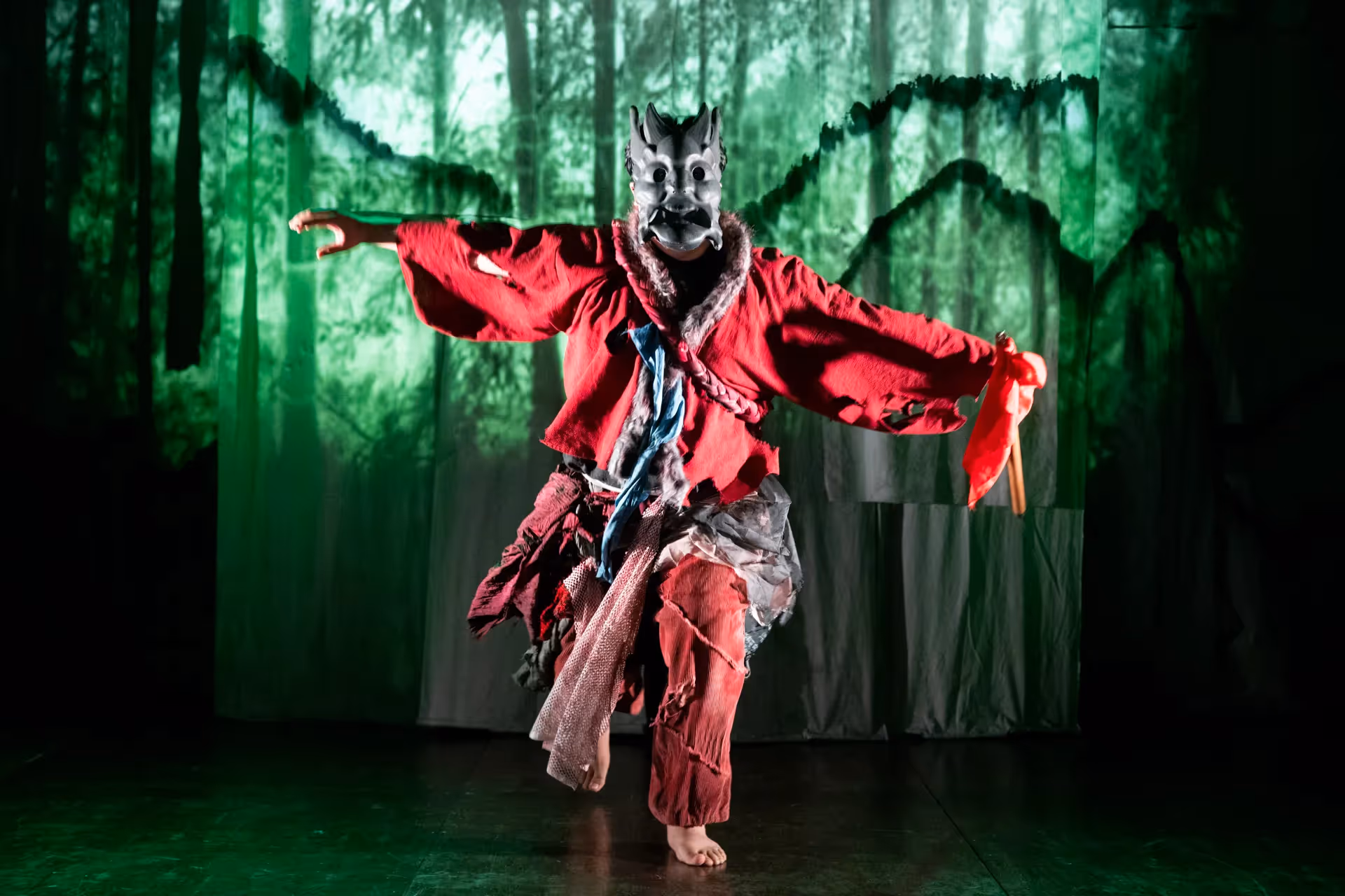 Festival di Spoleto performer in wolf mask dancing dramatically against green forest