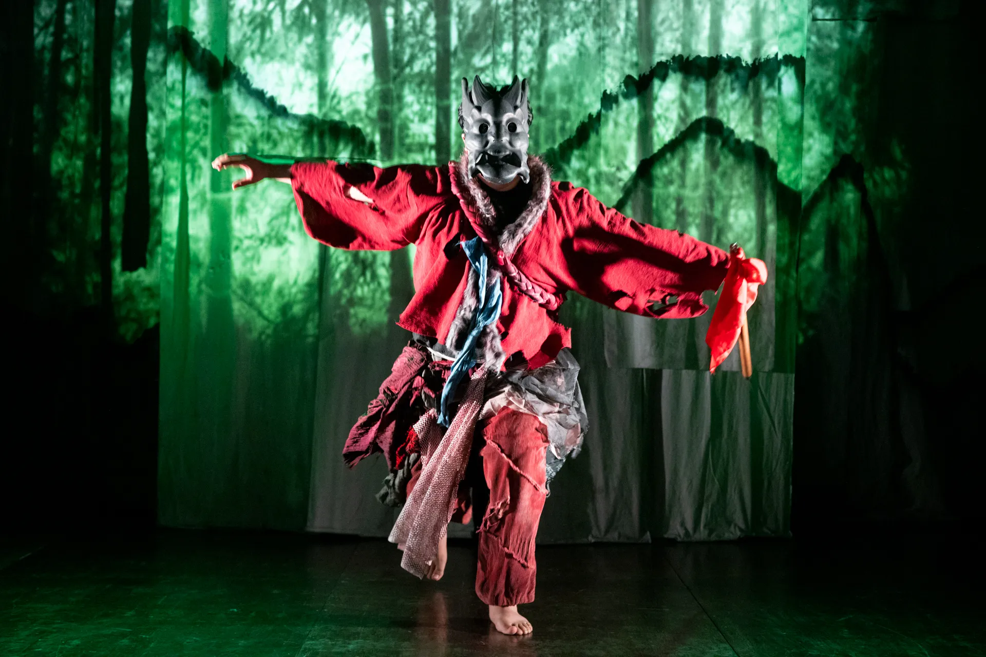 Festival di Spoleto performer in wolf mask dancing dramatically against green forest