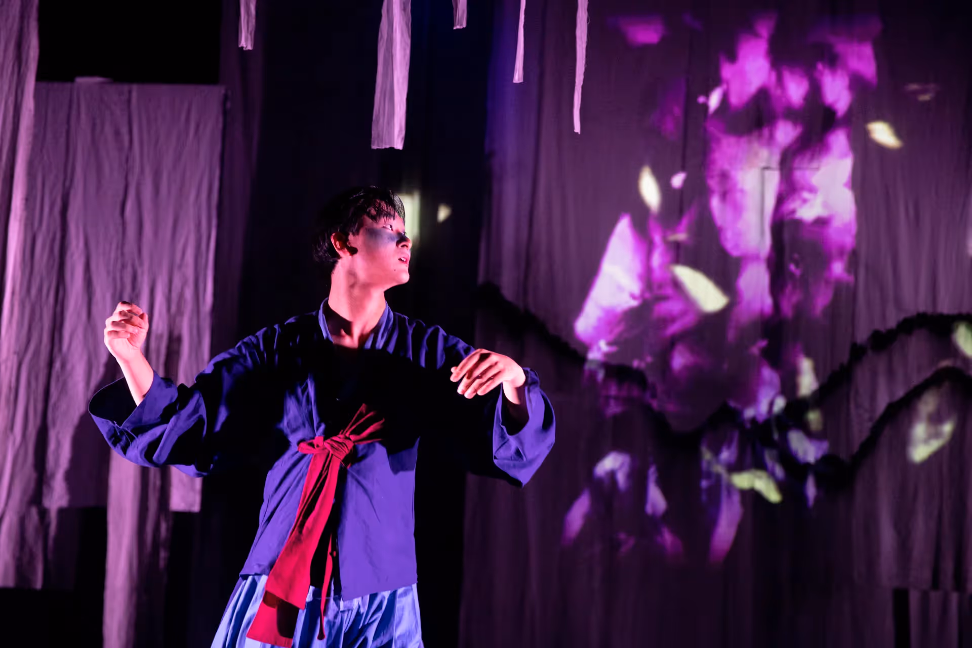 Dramatic performer at Festival di Spoleto with purple lighting and hanging fabrics