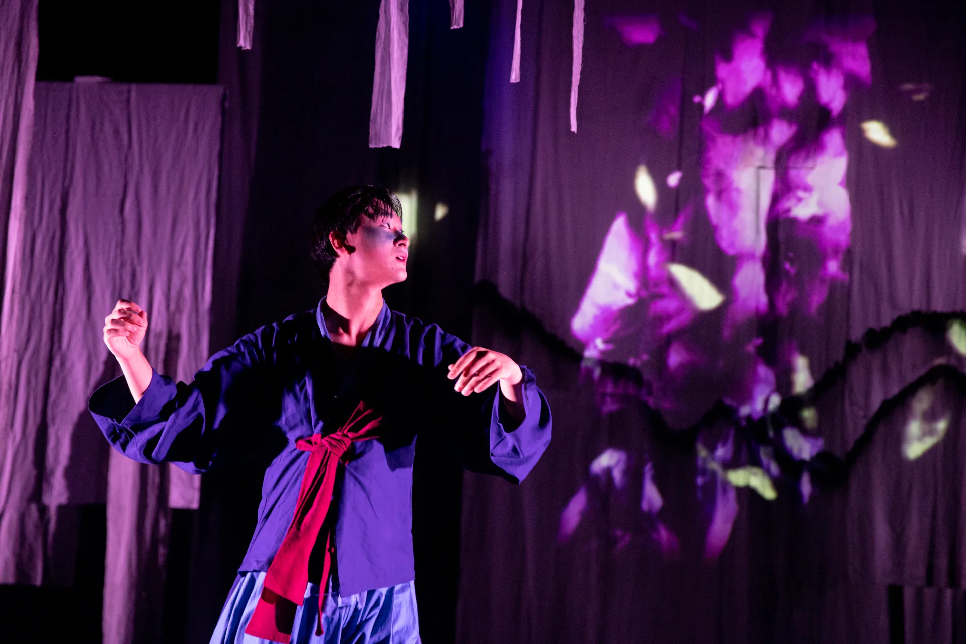 Dramatic performer at Festival di Spoleto with purple lighting and hanging fabrics