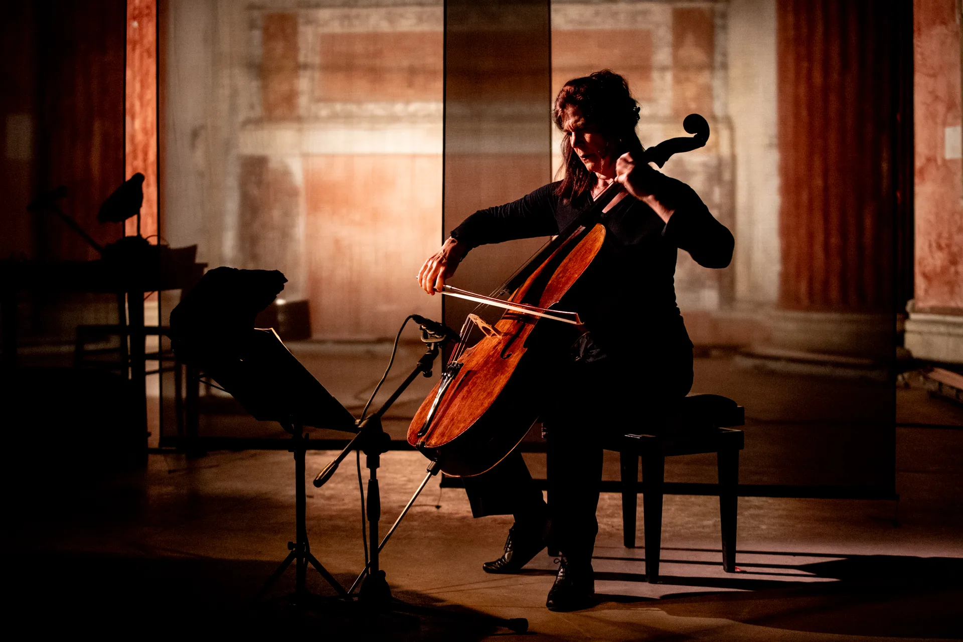 Cellist performing at Festival di Spoleto, dramatic lighting illuminates musical moment