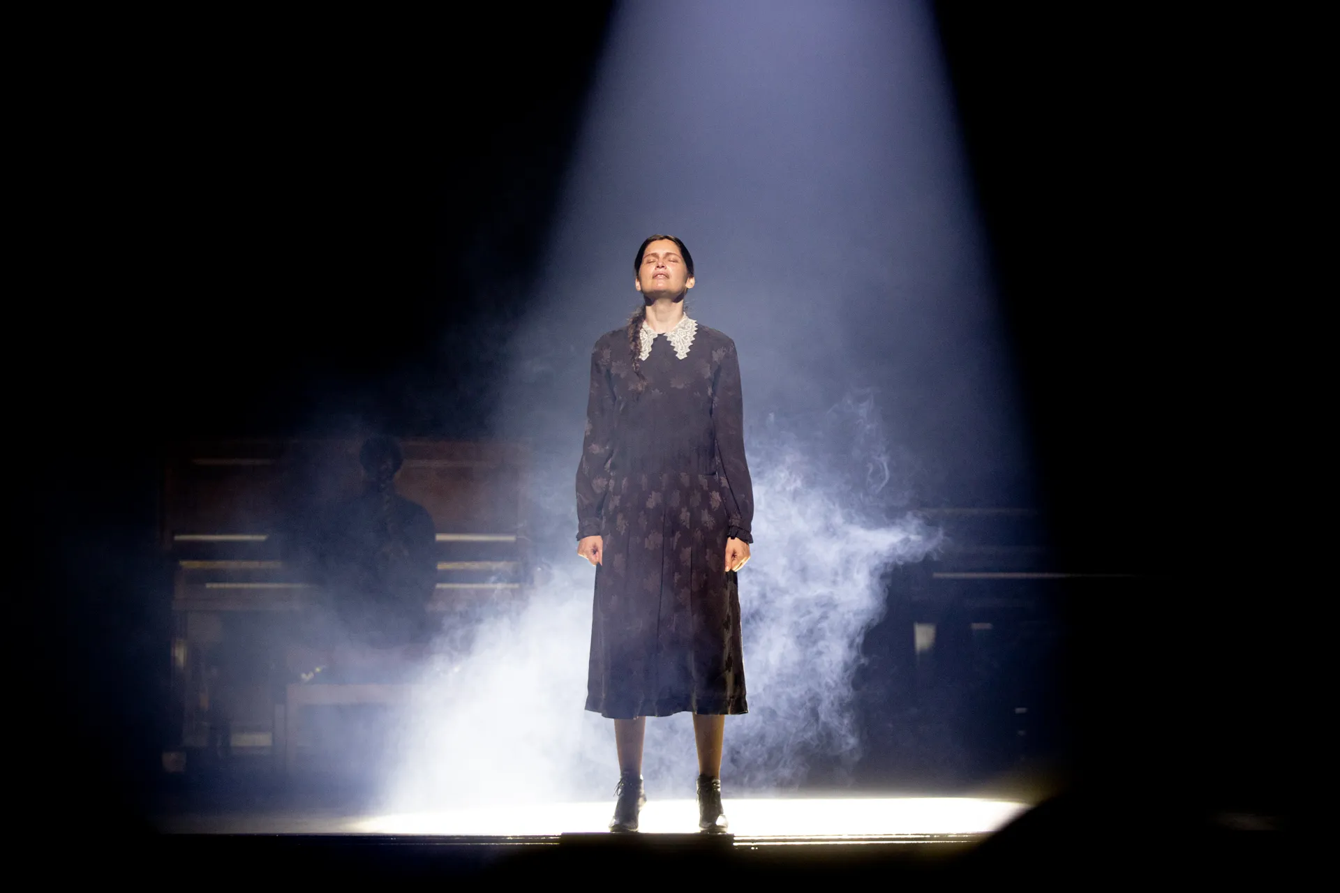 Dramatic performer at Festival di Spoleto, illuminated by spotlight amid smoky stage