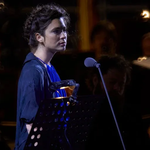 Performer on stage at Festival di Spoleto, wearing blue, standing near microphone