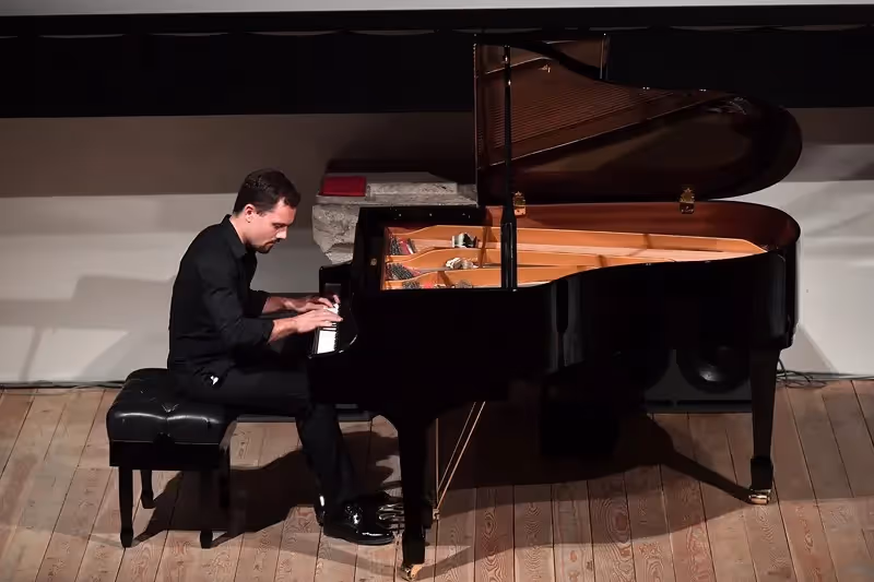 Pianist performing at Festival di Spoleto on a grand piano in black attire