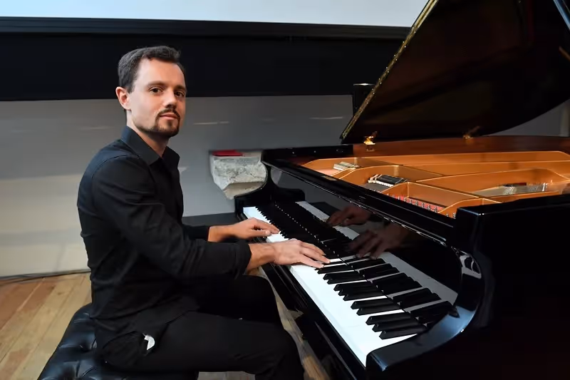 Pianist performing at Festival di Spoleto, seated at grand piano in black attire