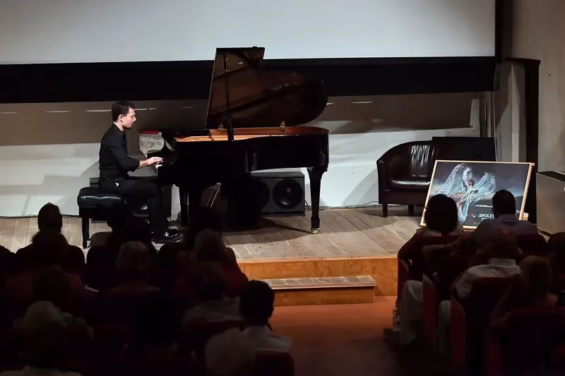 Pianist performs during Festival di Spoleto, playing grand piano on wooden stage