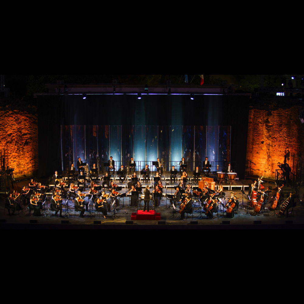 Orchestra sinfonica sul palco durante il Festival di Spoleto, illuminata suggestivamente