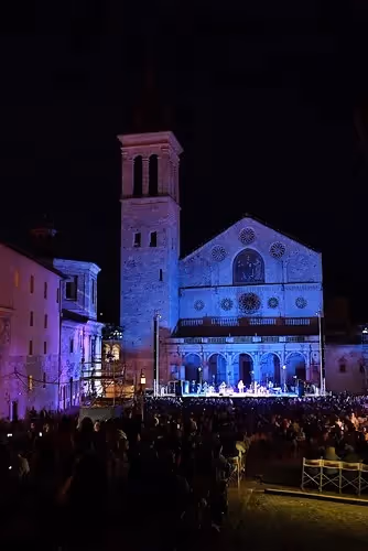 Duomo illuminato di notte durante il Festival di Spoleto con folla festante