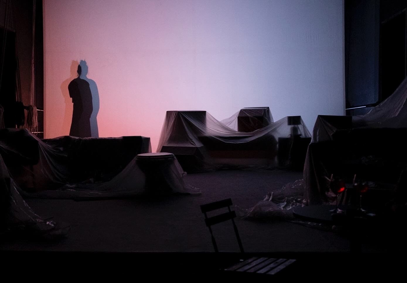 Scena teatrale suggestiva al Festival di Spoleto con ombre e oggetti coperti