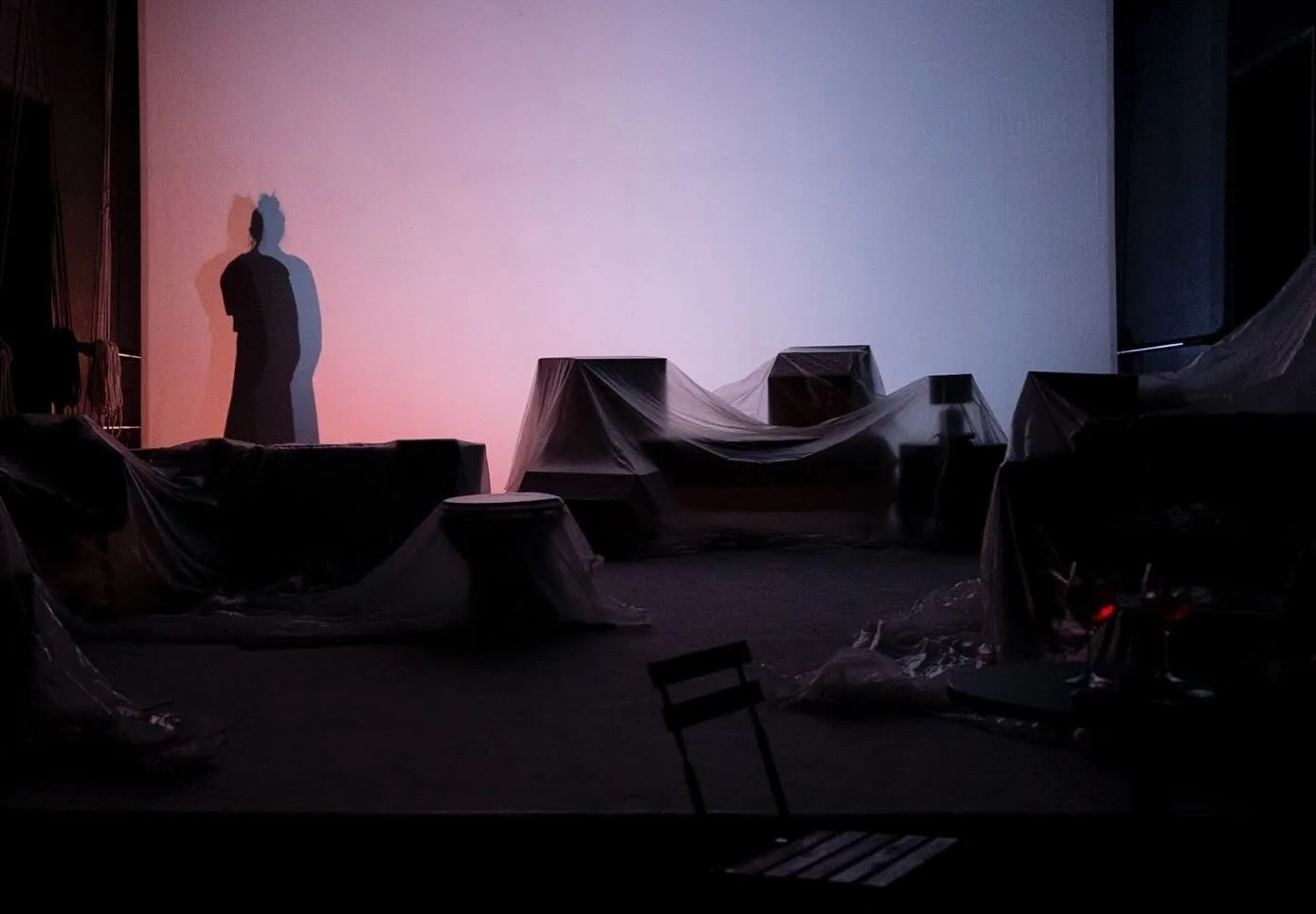 Scena teatrale suggestiva al Festival di Spoleto con ombre e oggetti coperti