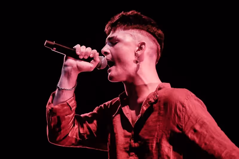 Passionate performer singing at Festival di Spoleto with intense red lighting