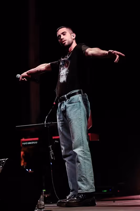 Performer on stage at Festival di Spoleto, passionately singing with outstretched arms
