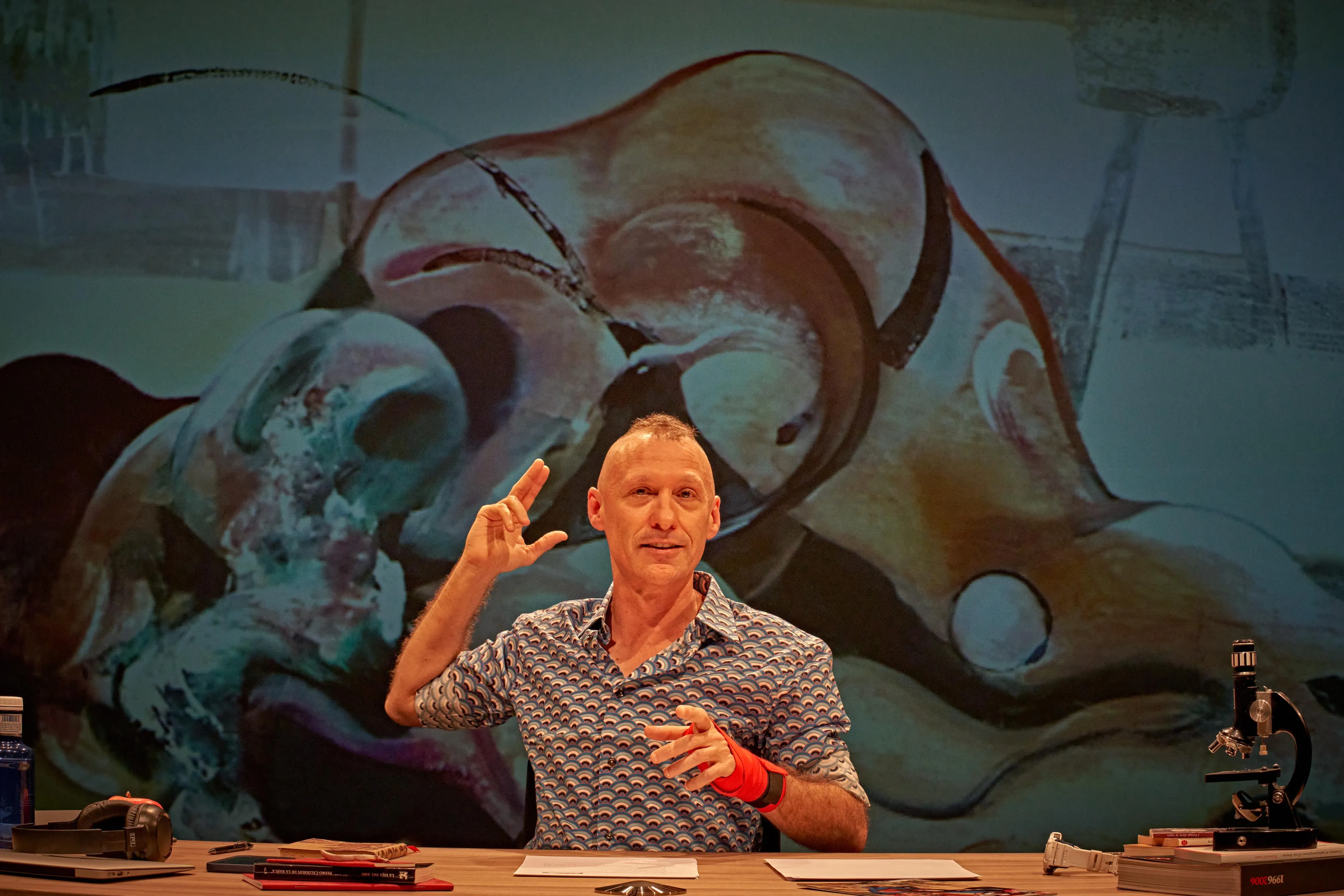 Ospite al Festival di Spoleto, presenta con gesto animato dietro sfondo artistico