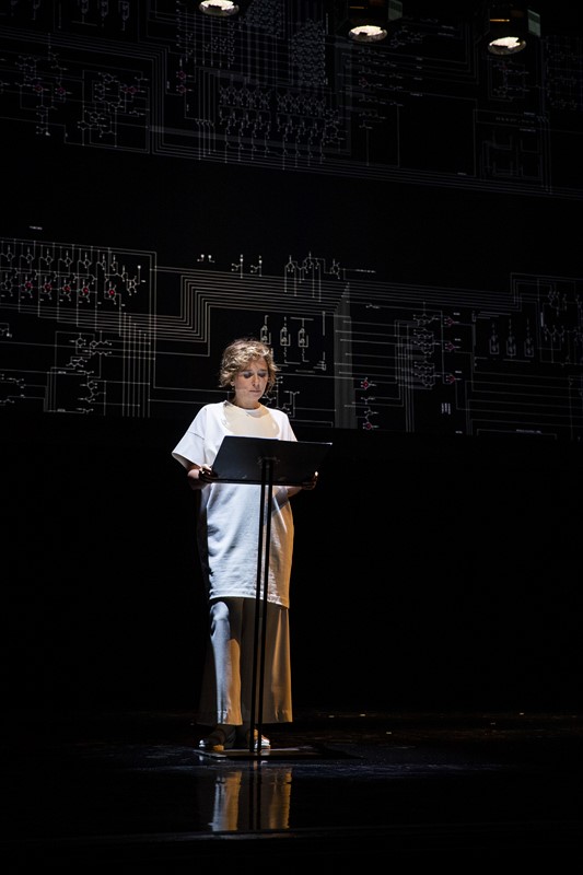 Artista sul palco durante il Festival di Spoleto, leggendo davanti a sfondo tecnico