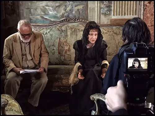 Festival di Spoleto interview scene with two people on ornate vintage sofa