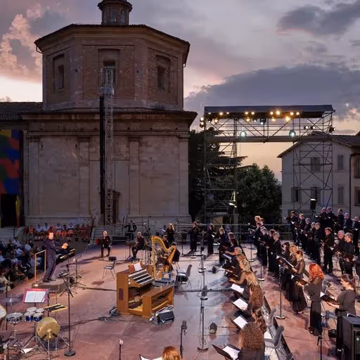 Festival di Spoleto: Outdoor orchestra performance at historic stone building during sunset