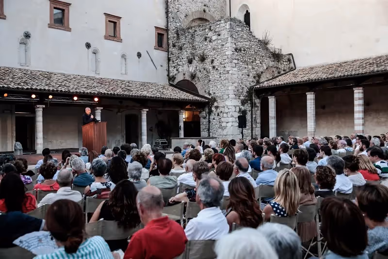 Festival di Spoleto outdoor event with speaker addressing crowded historic stone courtyard