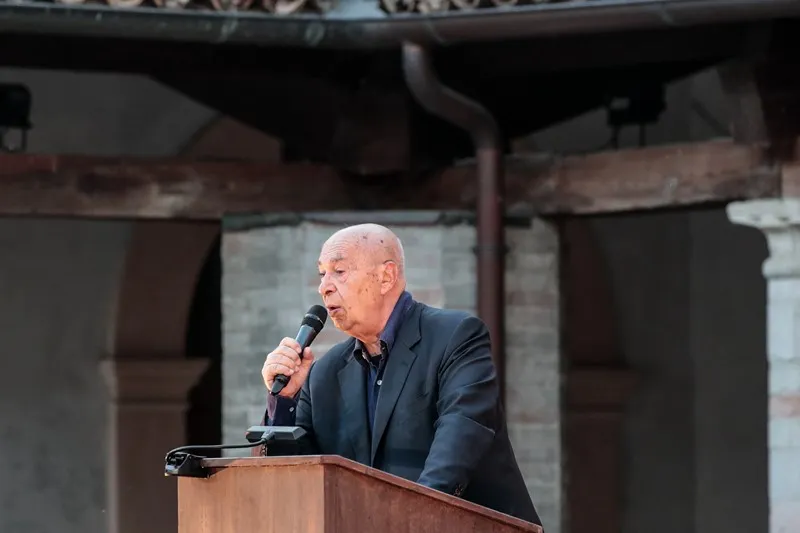 Speaker addresses audience at Festival di Spoleto, standing at wooden podium