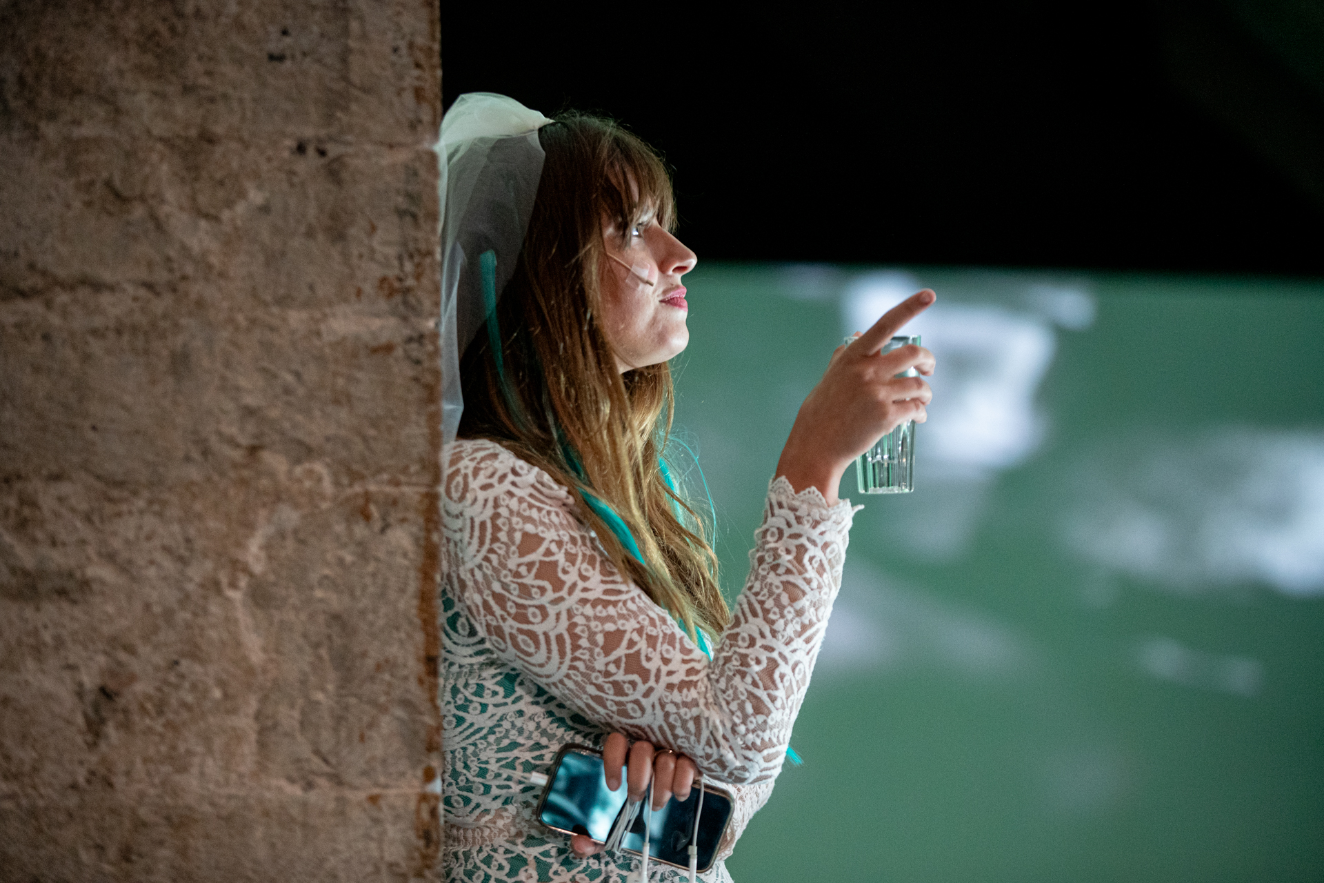 Performer at Festival di Spoleto wearing lace dress, holding glass backstage