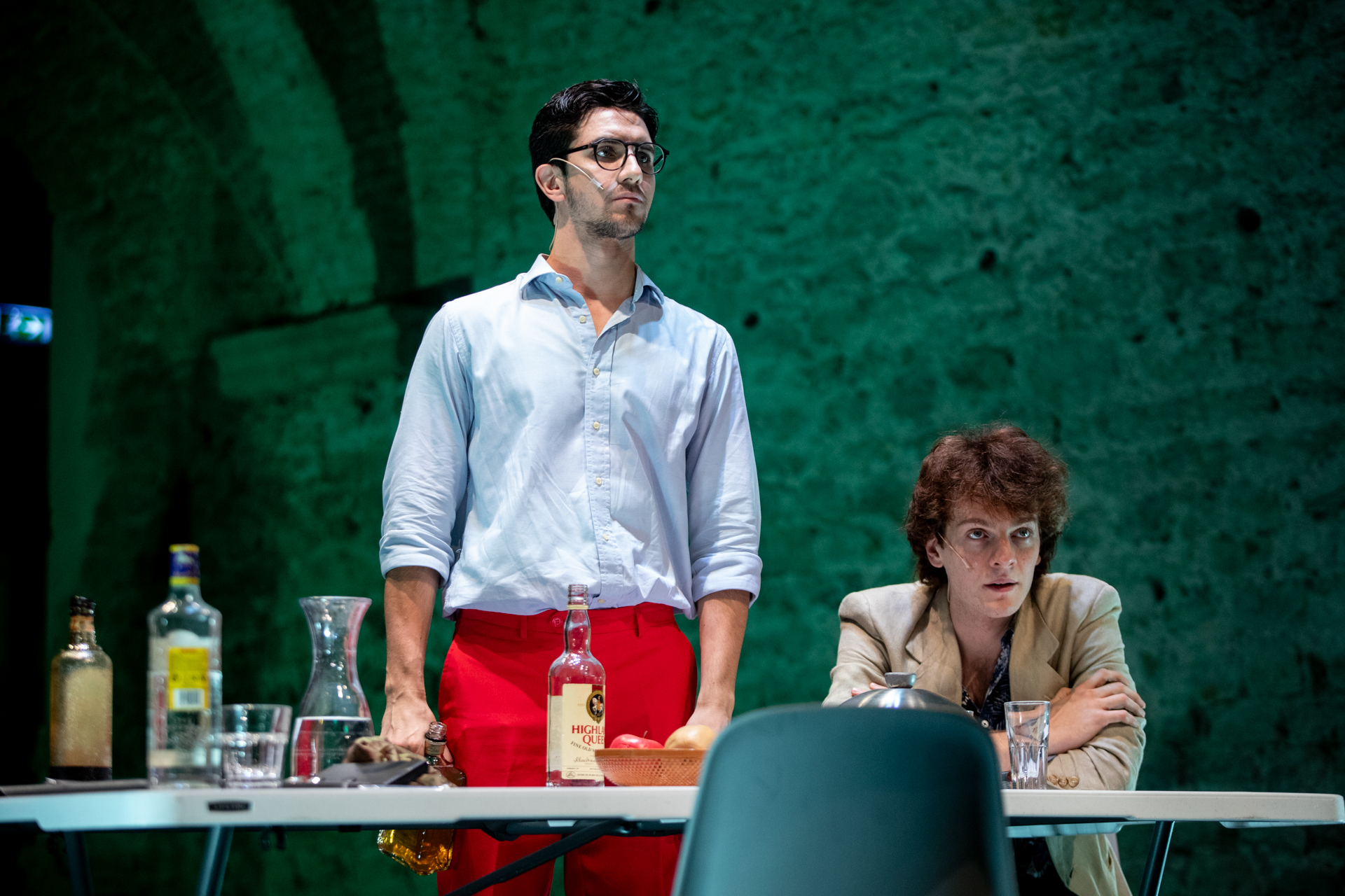 Dramatic theatrical scene at Festival di Spoleto with actors and whiskey bottles