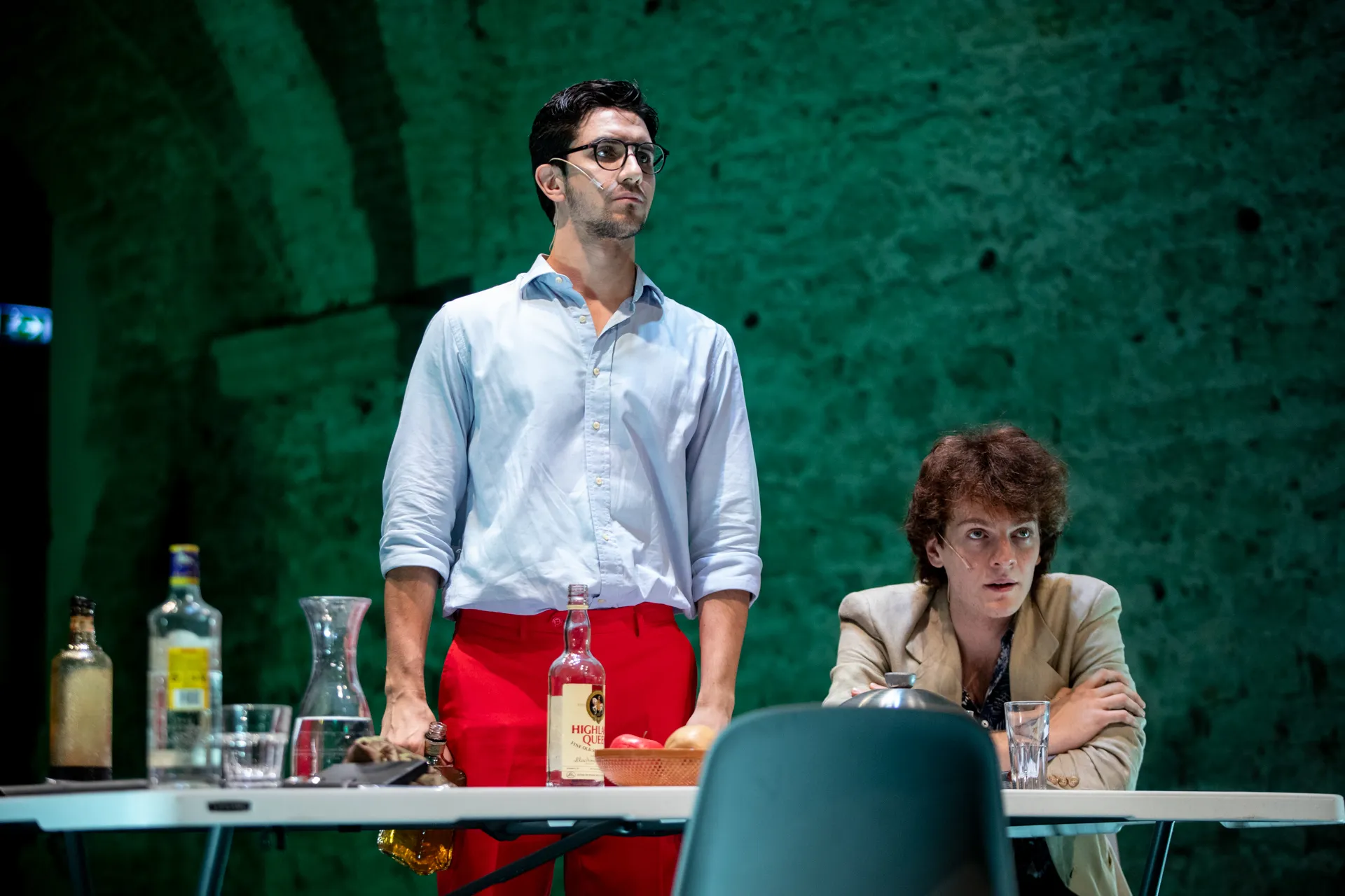 Dramatic theatrical scene at Festival di Spoleto with actors and whiskey bottles