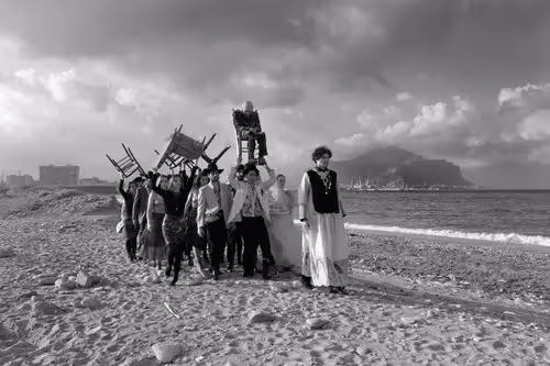 Festival di Spoleto performers walk dramatically on sandy beach with dramatic sky