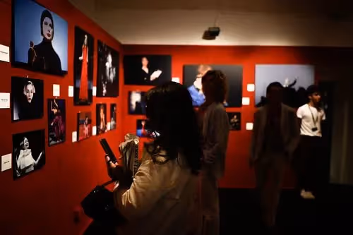 Mostra fotografica al Festival di Spoleto con pareti rosse e immagini in bianco e nero