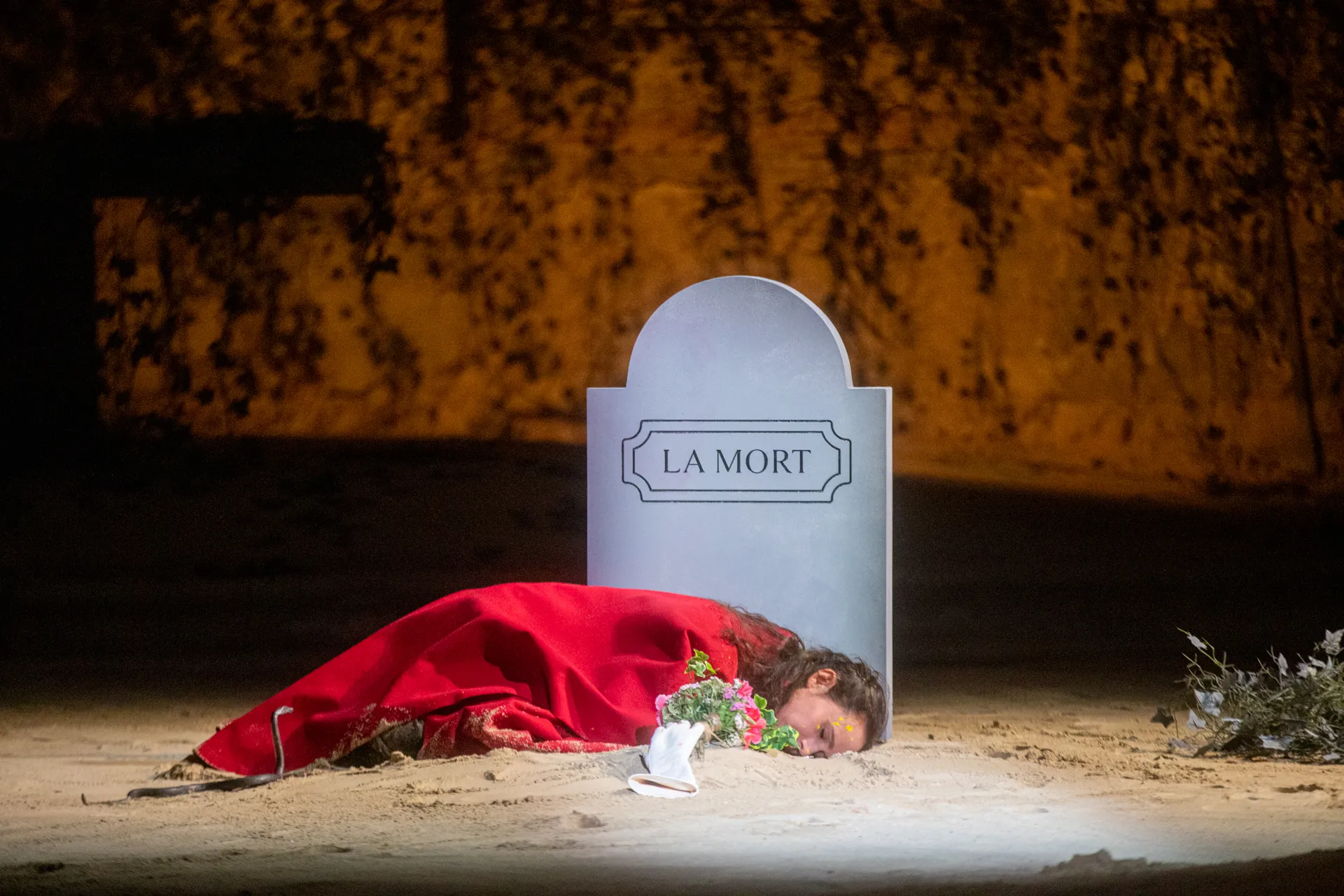 Scena drammatica al Festival di Spoleto, morte e fiori rossi sulla sabbia