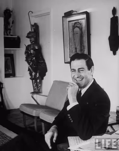 Smiling man in suit at Festival di Spoleto artistic event, surrounded by sculptures