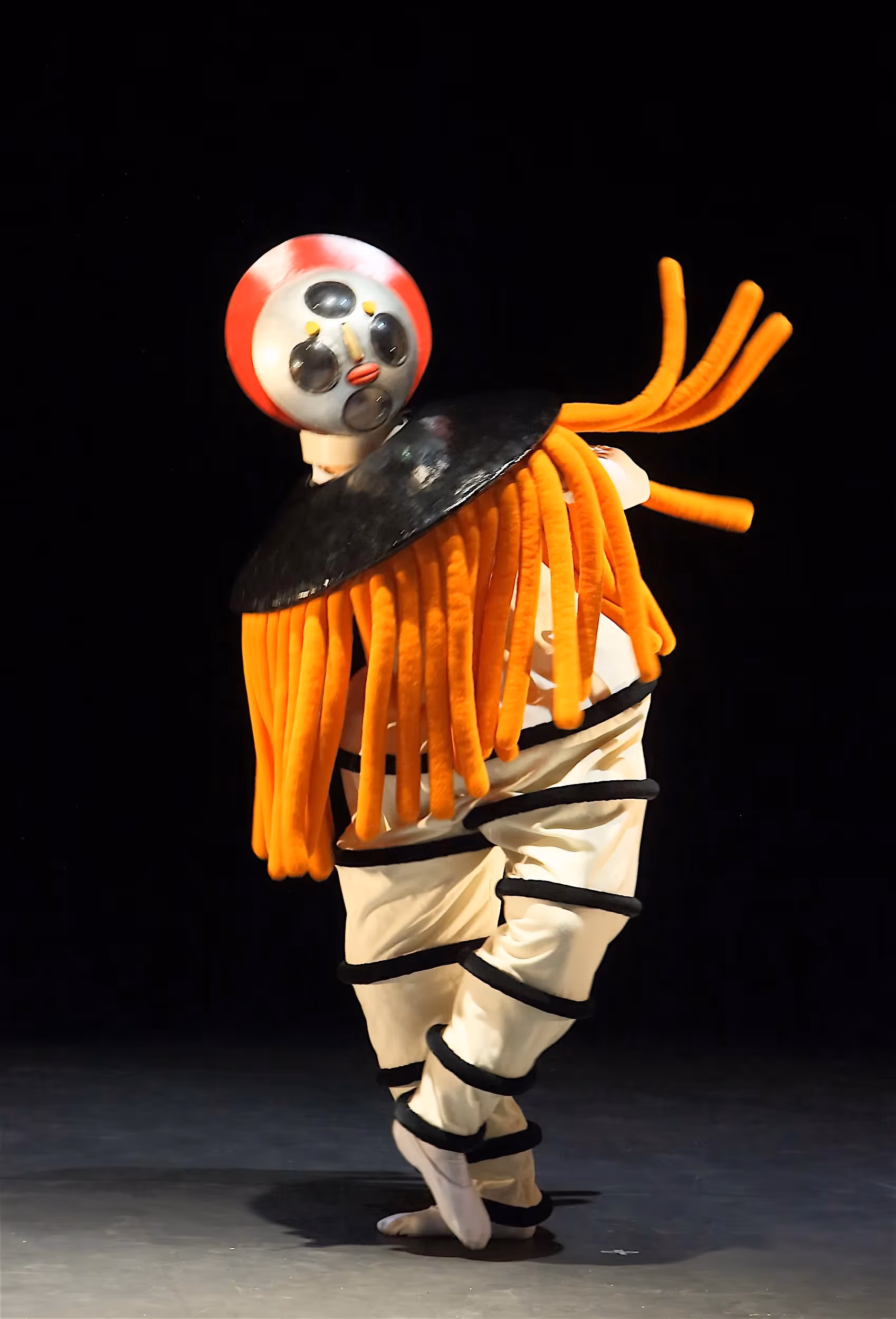 Surreal performer at Festival di Spoleto with orange dreadlocks and masked head