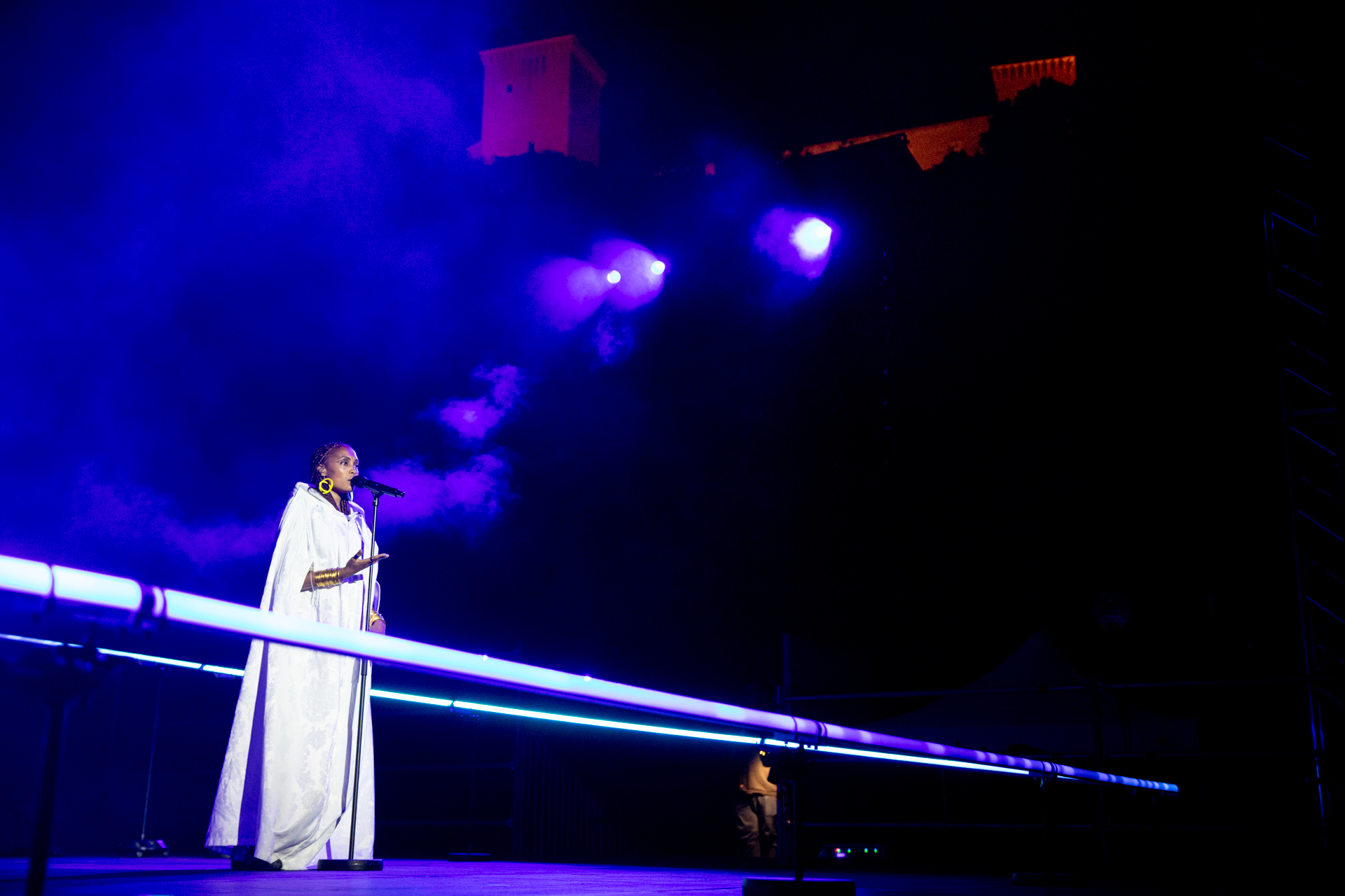 Performer in white dress singing at Festival di Spoleto with dramatic lighting