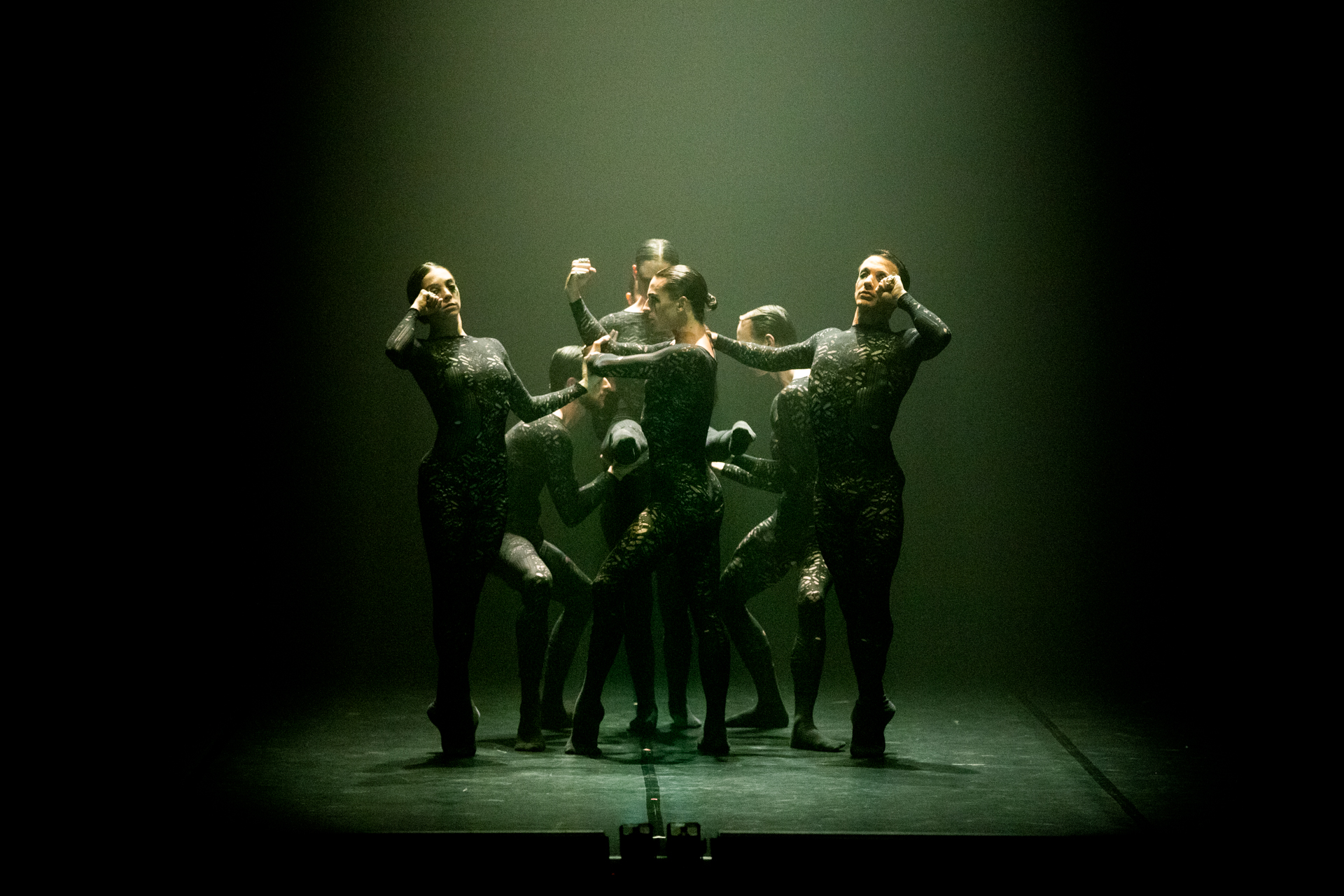 Danzatori in movimento suggestivo al Festival di Spoleto, atmosfera verde scura