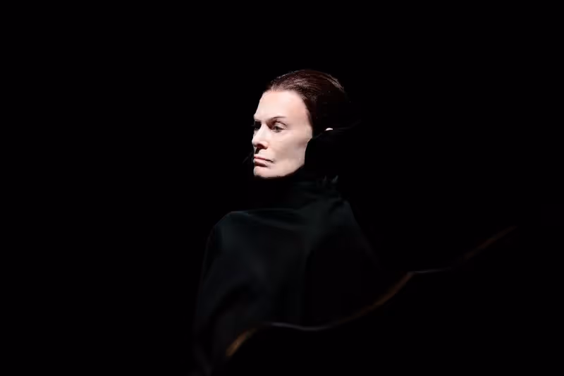 Dramatic performer at Festival di Spoleto, wearing black against dark background