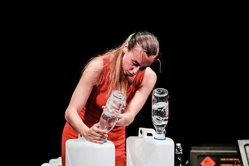 Performer in rosso al Festival di Spoleto, interagisce con contenitori d'acqua