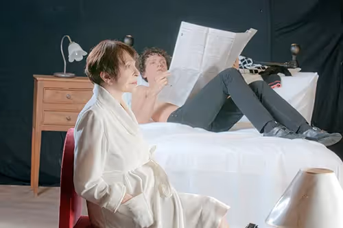 Festival di Spoleto performers rehearse dramatic scene on bed with newspaper