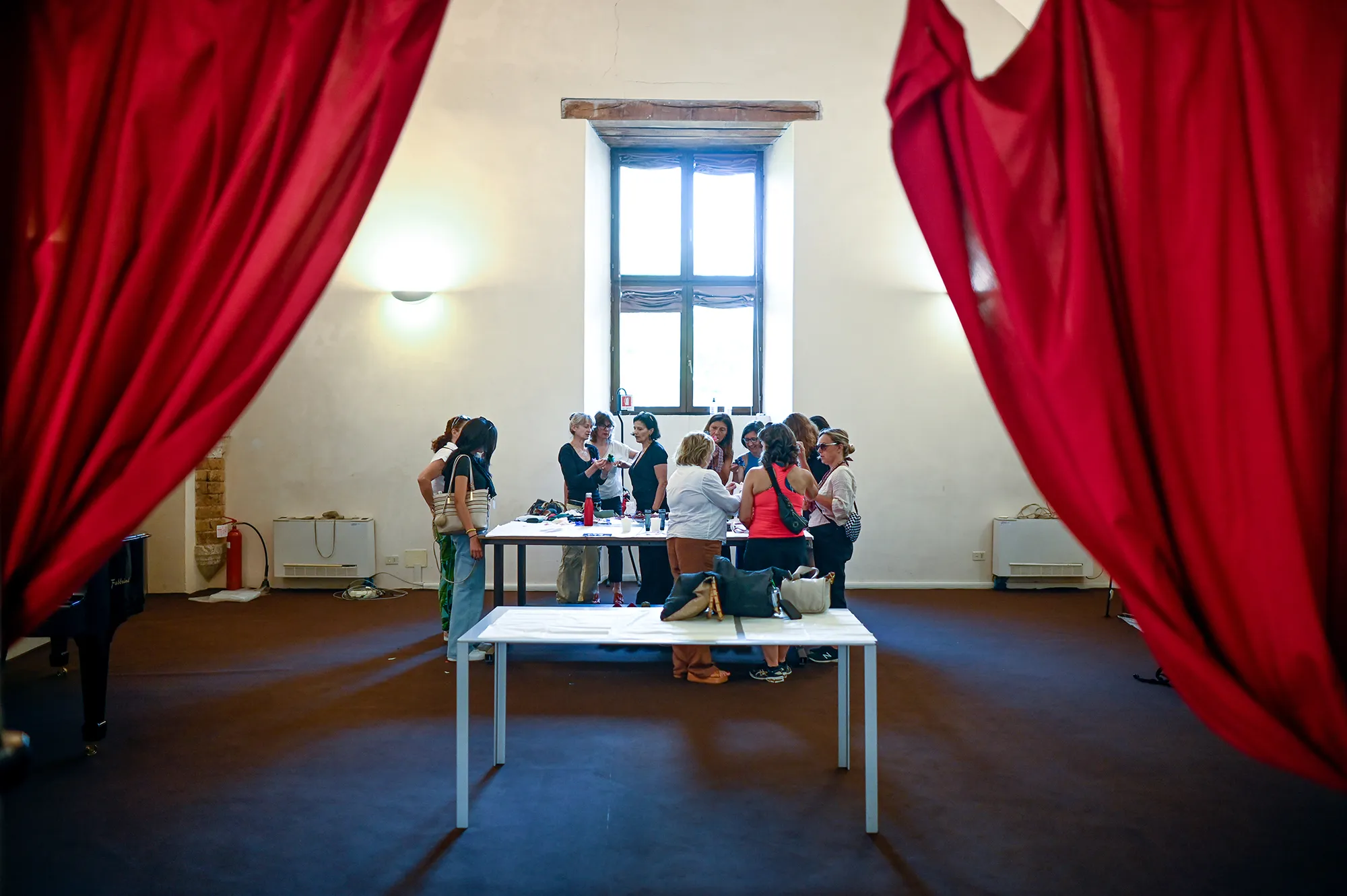 Partecipanti al Festival di Spoleto riuniti intorno a un tavolo con tende rosse