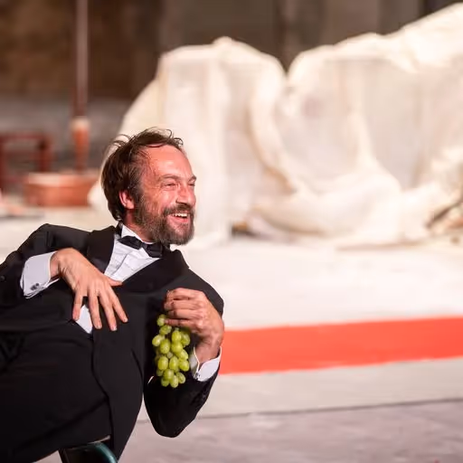 Artista sorridente al Festival di Spoleto con un grappolo d'uva