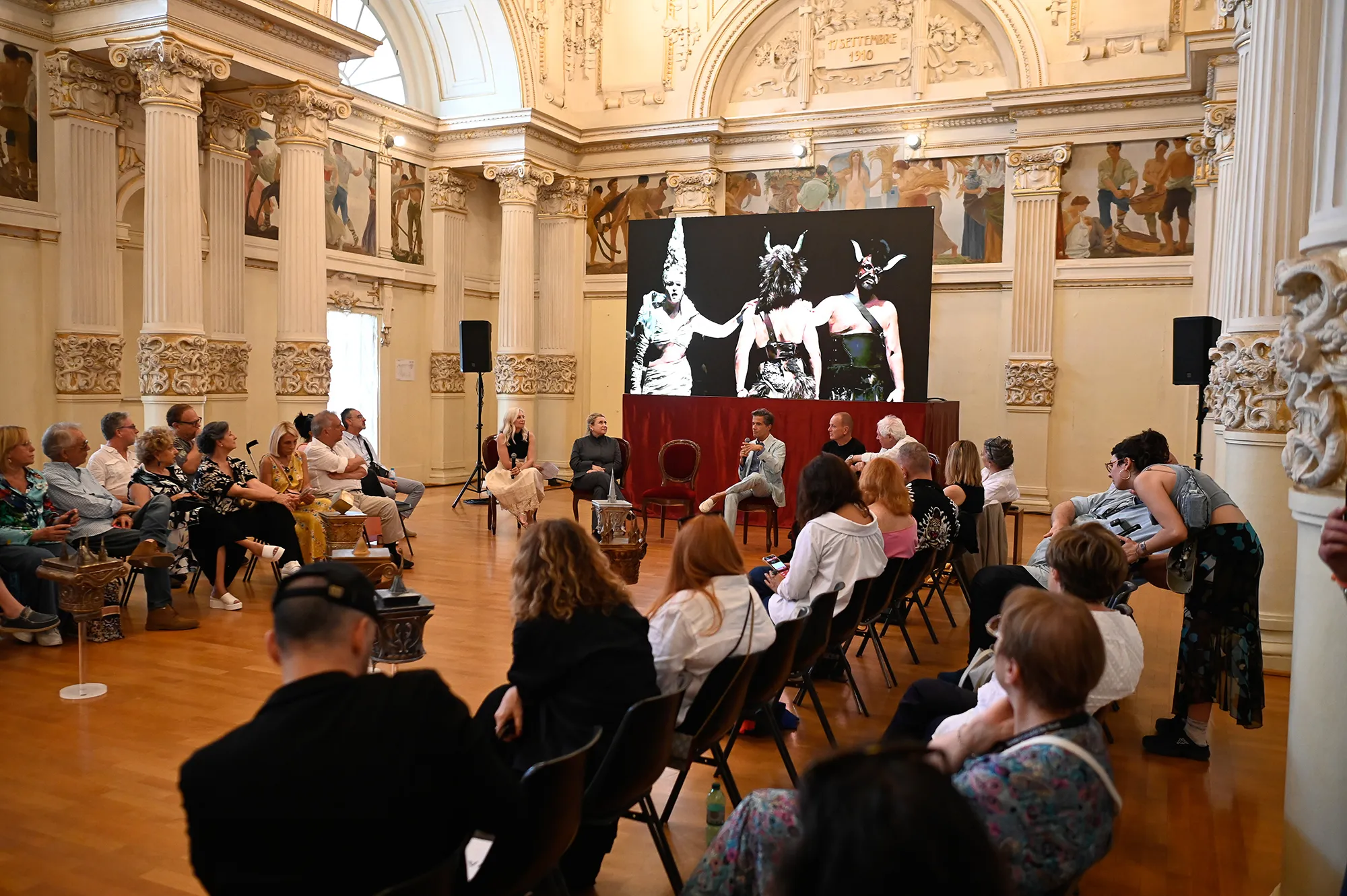 Conferenza al Festival di Spoleto con pannello artistico in elegante sala storica